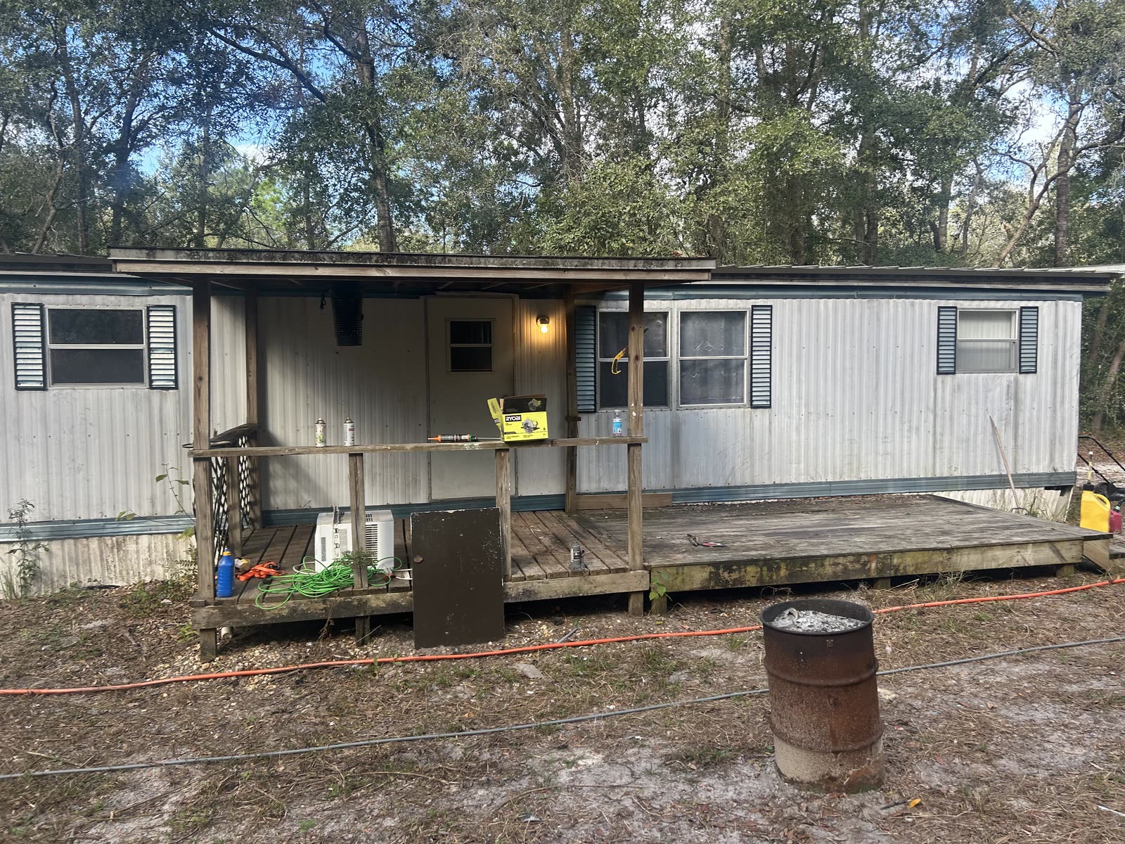Mobile home with mildew-stained white siding and a weathered grey deck