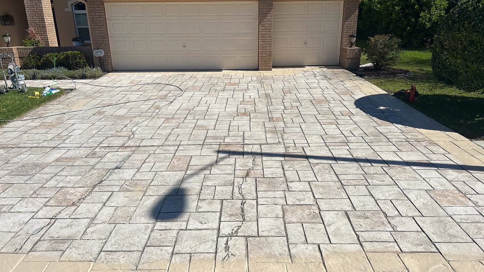 Freshly cleaned paver driveway leading to a two-car garage