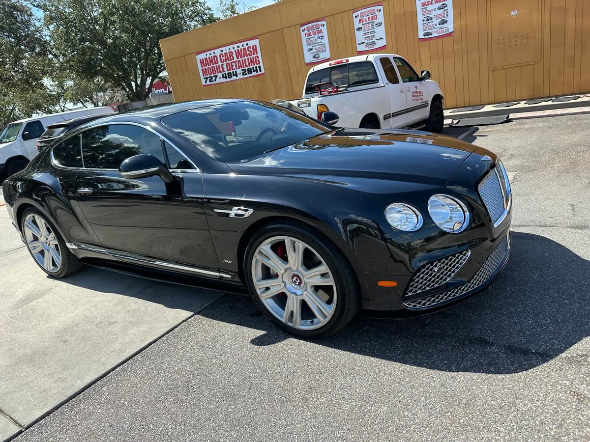 Black Bentley coupe gleaming after a hand wash at The Wisemen lot