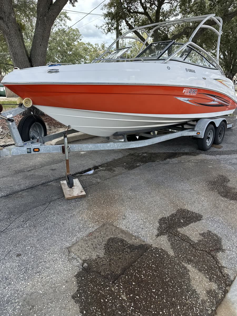 Orange and white bowrider boat on its trailer after a wash